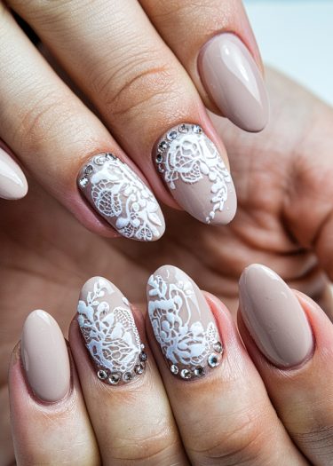 Elegant nude lace nail art featuring intricate designs and sparkling rhinestones for a luxurious look.