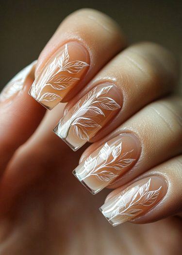 Elegant nude nail art with intricate white leafy designs and a glossy finish.