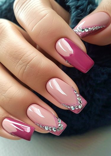 Elegant nude pink and burgundy nail art with rhinestones on a stylish hand.