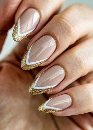 Elegant almond-shaped nude nails with gold glitter tips, showcasing trendy nail art design.