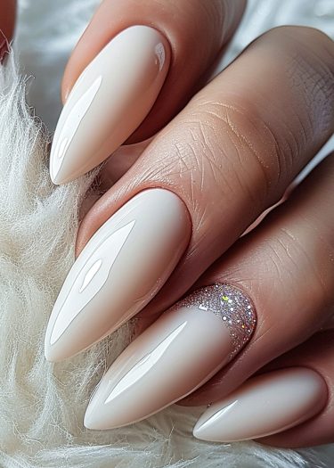 Elegant nude almond stiletto nails with a glossy finish and subtle glitter accents.