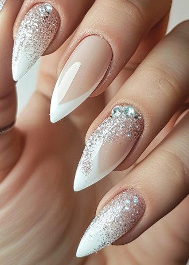 Sophisticated stiletto nails with nude polish, glitter, and rhinestones for an elegant look.