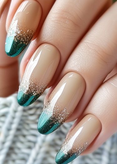 Elegant nude and teal nail art with glitter ombre on almond-shaped nails.