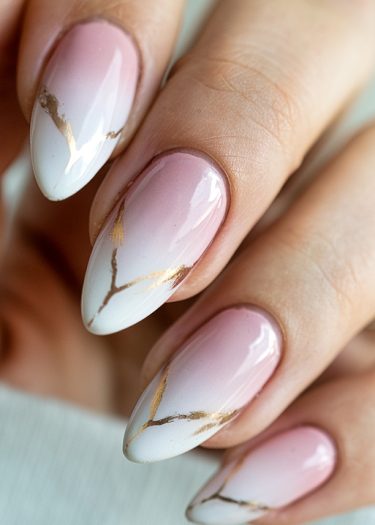 Elegant ombre nail design with gold accents in a glossy almond shape.