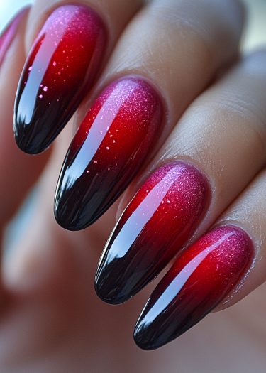 Elegant ombre nails with black and shimmering red gradient, featuring sparkling glitter accents.