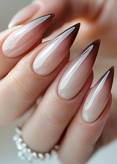 Stiletto ombré nails in glossy nude to burgundy, showcasing elegant nail artistry and grooming.