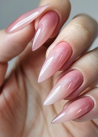 Elegant stiletto nails with vibrant pink ombre and sparkling glitter for a sophisticated look.