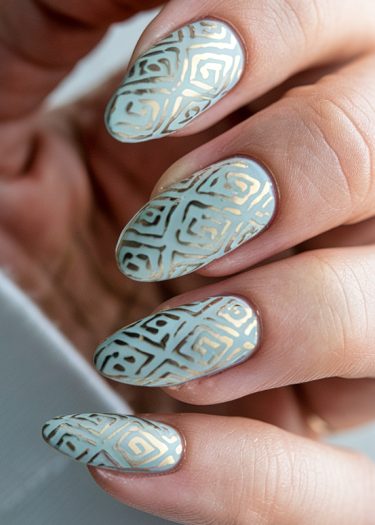 Elegant pastel blue manicure with intricate gold geometric patterns for a luxurious touch.