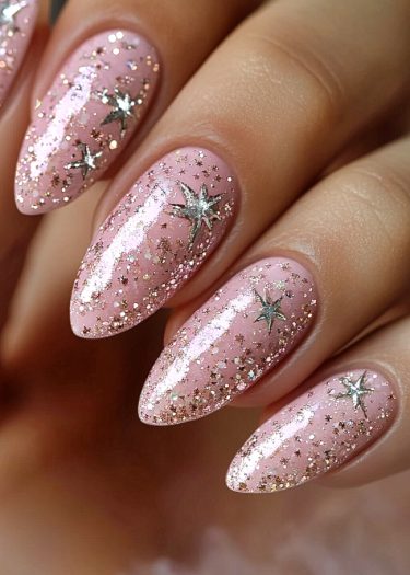 Elegant pastel pink almond-shaped nails adorned with silver stars and sparkling glitter.