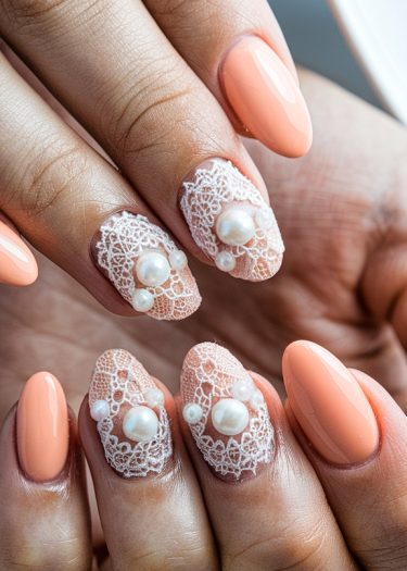 Elegant peach nails with intricate lace designs and pearl accents for a sophisticated look.