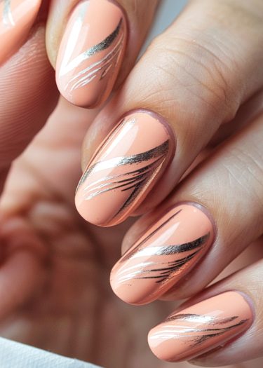 Elegant peach nails with intricate metallic silver designs for a sophisticated manicure look.