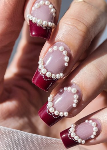 Elegant maroon and pink nail art with pearls and silver glitter for a luxurious look.