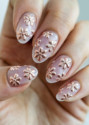 Elegant almond-shaped nails feature intricate rose gold floral designs on a soft pink base.