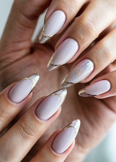 Elegant almond-shaped nails with soft pink polish and shimmering gold-silver tips enhance beauty.