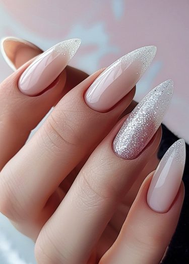 Elegant pink almond-shaped nails with silver glitter ombré for a chic, sophisticated look.