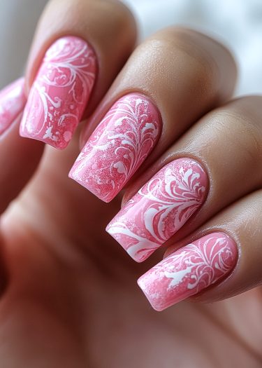 Elegant pink nail art with intricate white floral designs for a stylish manicure.