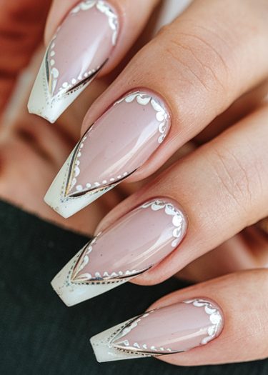 Elegant nude almond nails with geometric silver and white designs for a sophisticated manicure.