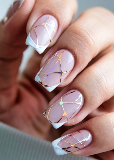 Elegant pink nail art with gold geometric patterns and French tips for a sophisticated look.