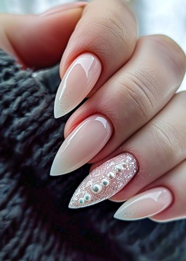 Elegant stiletto pink nails with glitter detail on the ring finger, showcasing exquisite nail art.