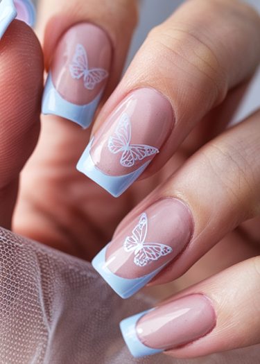 Elegant pink nails with butterfly art and blue French tips in a close-up manicure.