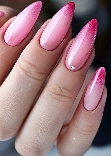 Elegant pink ombré stiletto nails with rhinestone accent for a glamorous, polished look.