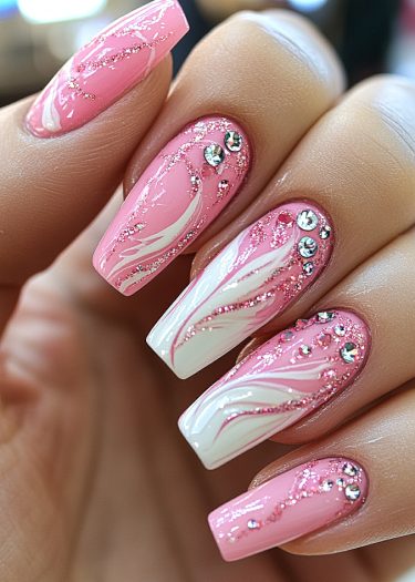 Elegant pink and white acrylic nails with intricate designs and sparkling rhinestones.