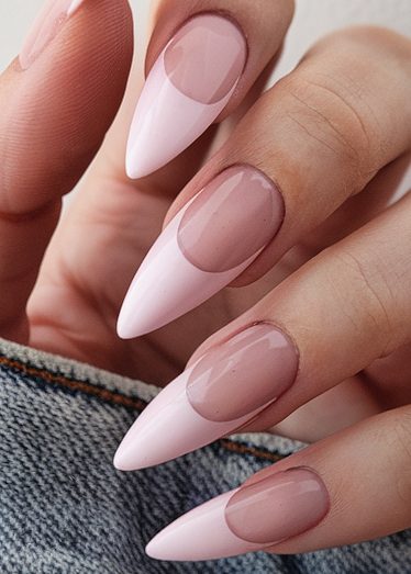 Stunning pink stiletto nails with a glossy finish and elegant gradient design on denim.