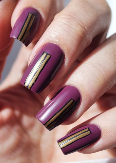 Elegant plum nails with luxurious gold stripes for a sophisticated manicure look.