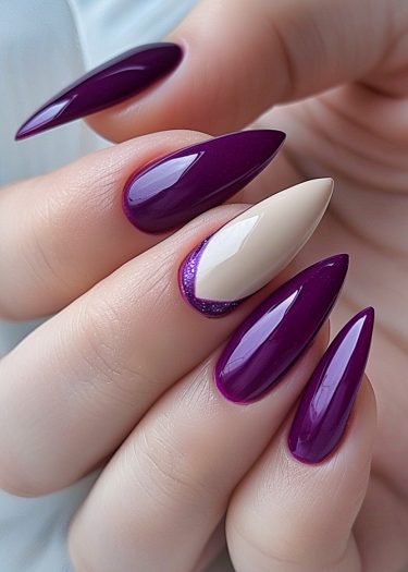 Elegant stiletto nails in deep purple with a chic accent nail and glittery details.