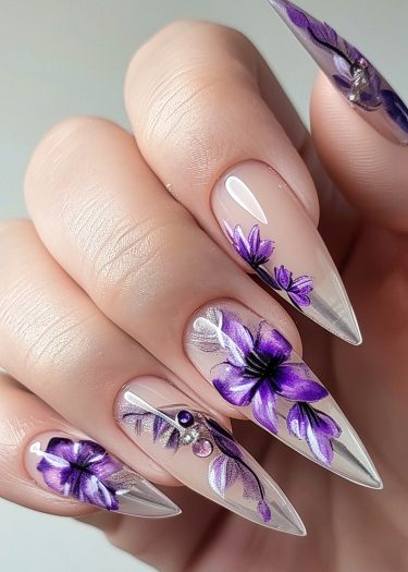 Elegant purple floral nail art with stiletto tips and dazzling embellishments for a luxurious look.