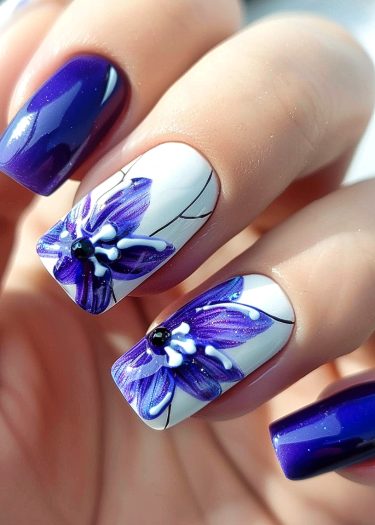 Elegant purple flower nail art with glossy finish and artistic designs on medium-length nails.