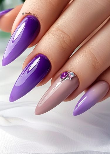 Elegant stiletto nails featuring a purple gradient and luxurious embellishments for modern nail art.