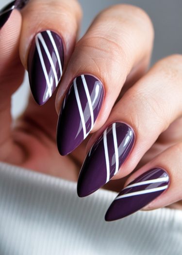 Elegant purple manicure with unique white stripes on almond-shaped nails.