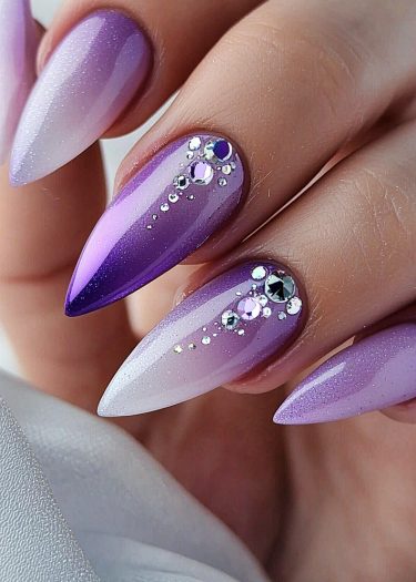 Elegant purple ombre nails with rhinestones, showcasing a sophisticated and glamorous manicure.