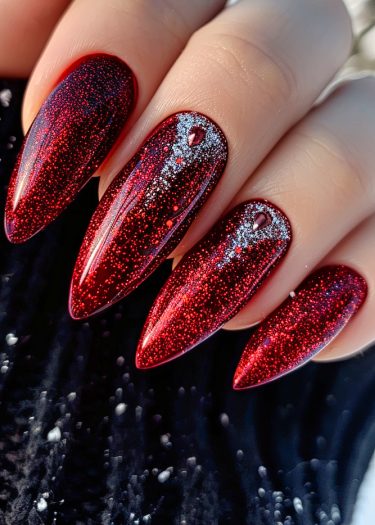 Sophisticated long red almond nails with glittery accents for a glamorous, elegant look.