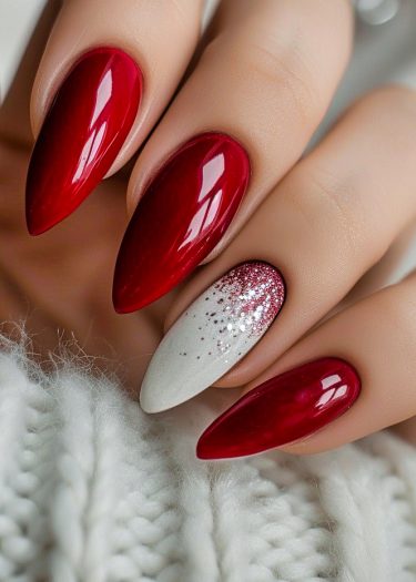 Elegant red almond-shaped nails with a glittery accent design for a chic manicure.