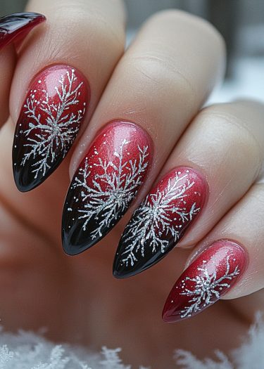 Elegant stiletto nails feature a red to black gradient with sparkling snowflakes for a festive look.