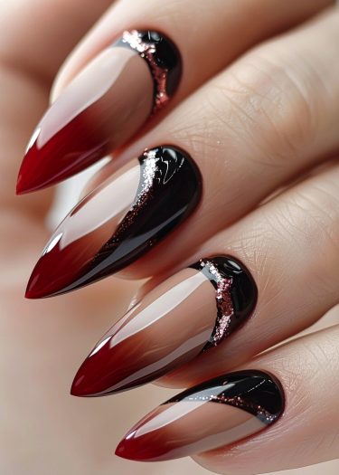 Stunning stiletto nails feature an ombre red-black design with elegant glitter accents.