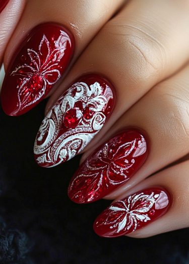 Elegant red nail art featuring intricate floral designs and sparkling rhinestones.