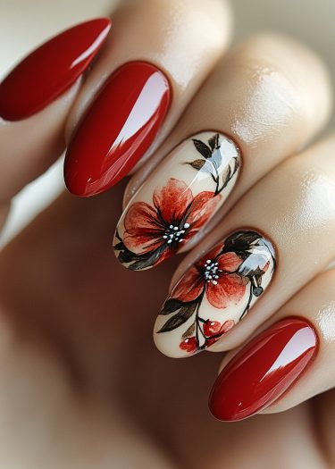 Elegant red floral nails featuring intricate designs on almond-shaped manicured nails.