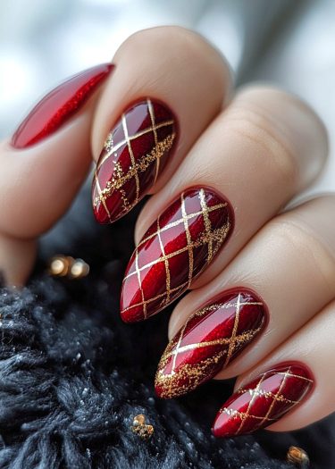 Elegant red and gold nail art with intricate designs and glitter for a luxurious look.