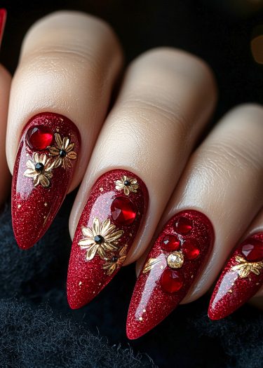 Elegant red and gold nail art featuring glitter, rhinestones, and floral designs on deep black.