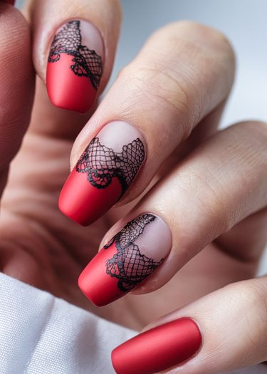 Elegant red matte nails with intricate black lace designs for a sophisticated manicure.