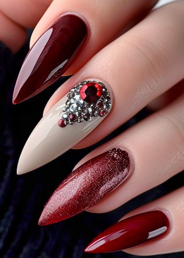 Elegant red stiletto nails with glitter and rhinestones for a luxurious manicure look.