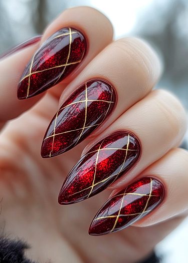 Elegant red stiletto nails with gold crisscross design for a glamorous and sophisticated look.