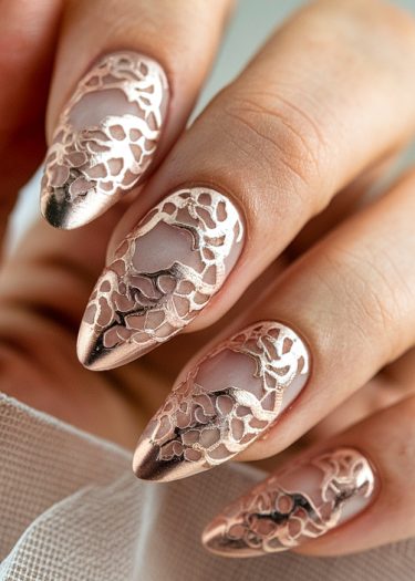 Elegant rose gold nail art featuring intricate lace designs on almond-shaped nails.