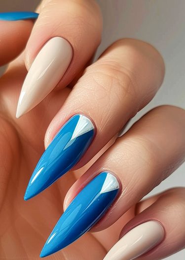 Elegant almond-shaped nails featuring beige and vibrant blue art with geometric accents.