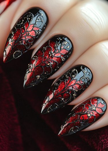 Elegant stiletto nails with intricate black, red, and metallic designs on a velvet background.