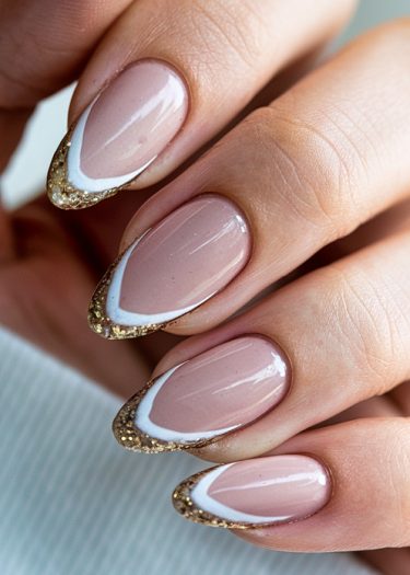 Elegant almond-shaped nail art featuring nude, white, and gold glitter for a sophisticated look.