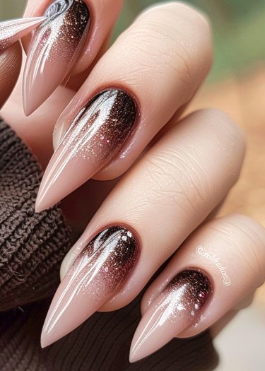 Elegant almond stiletto nails featuring a brown to nude pink ombre and glitter design.